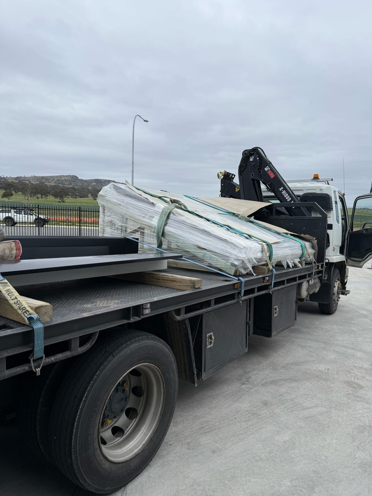 Crane truck carrying a wrapped load of building materials